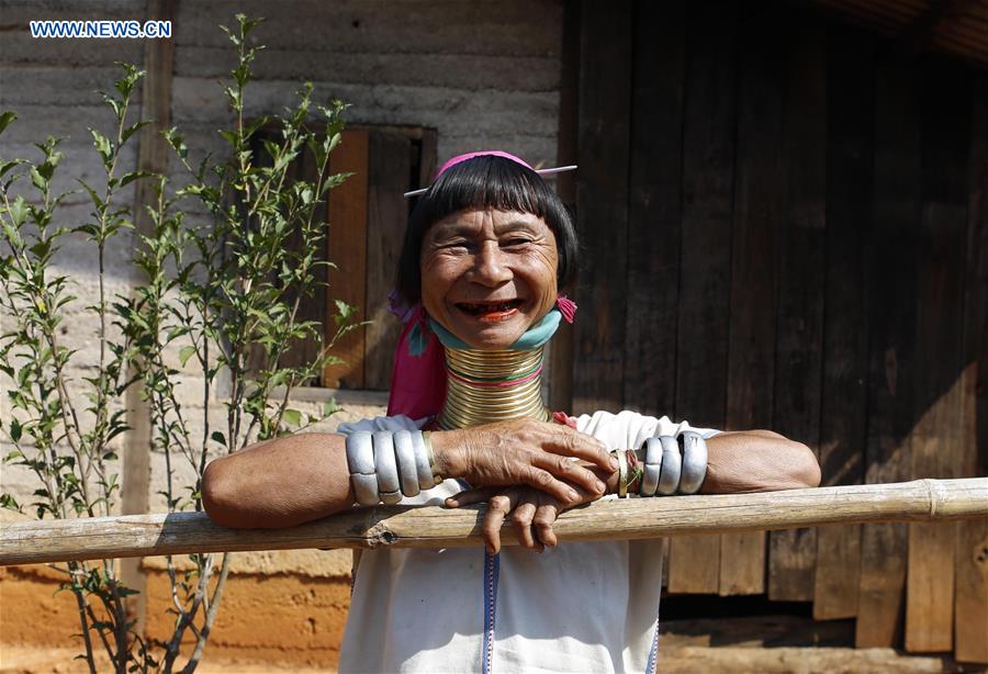 A Padaung woman with brass rings around her neck smiles as she stands in front of her home in Panpet Village, Demoso Township, Kayah State, Myanmar, April 11, 2016.