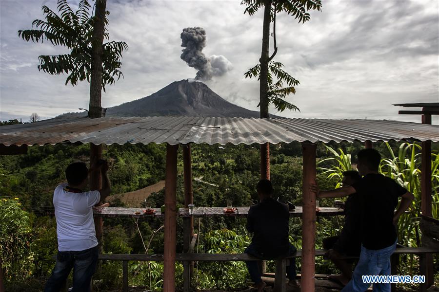 A woman watches the eruption of Mount Sinabung at Tiga Pancur village in Karo district, North Sumatra, Indonesia, July 24, 2016.